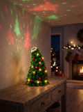 Fir Mini Christmas Tree Projector Light on a wooden console casting festive patterns