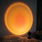 Warm amber sunset disc projected across a bedroom wall by the Ember lamp at night